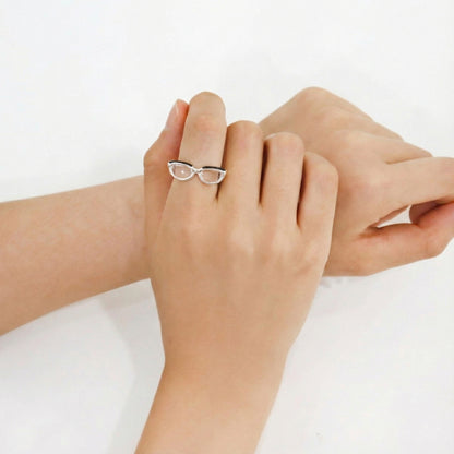  Front view of adjustable silver spectacle ring on middle finger, displaying transparent lens design and open band structure 