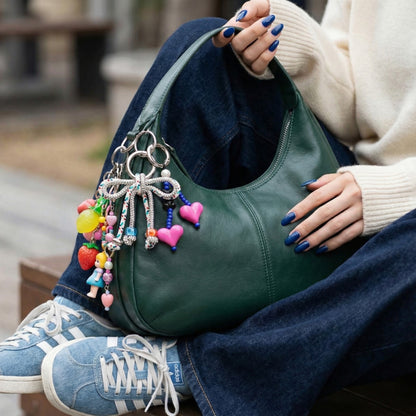 Green leather hobo bag with colorful rhinestone bow keychain layered with character charms and heart pendants