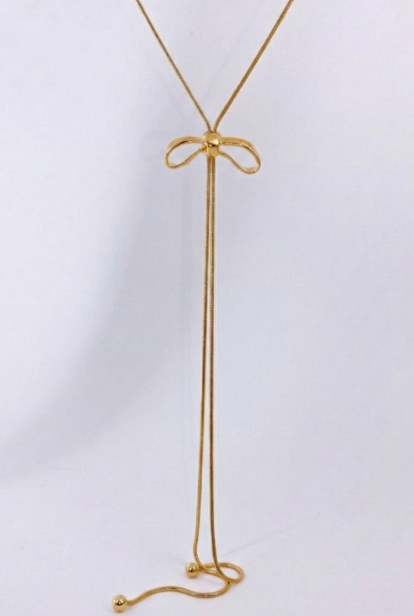 Close-up of gold ribbon bow pendant with sliding mechanism - 65cm adjustable lariat necklace