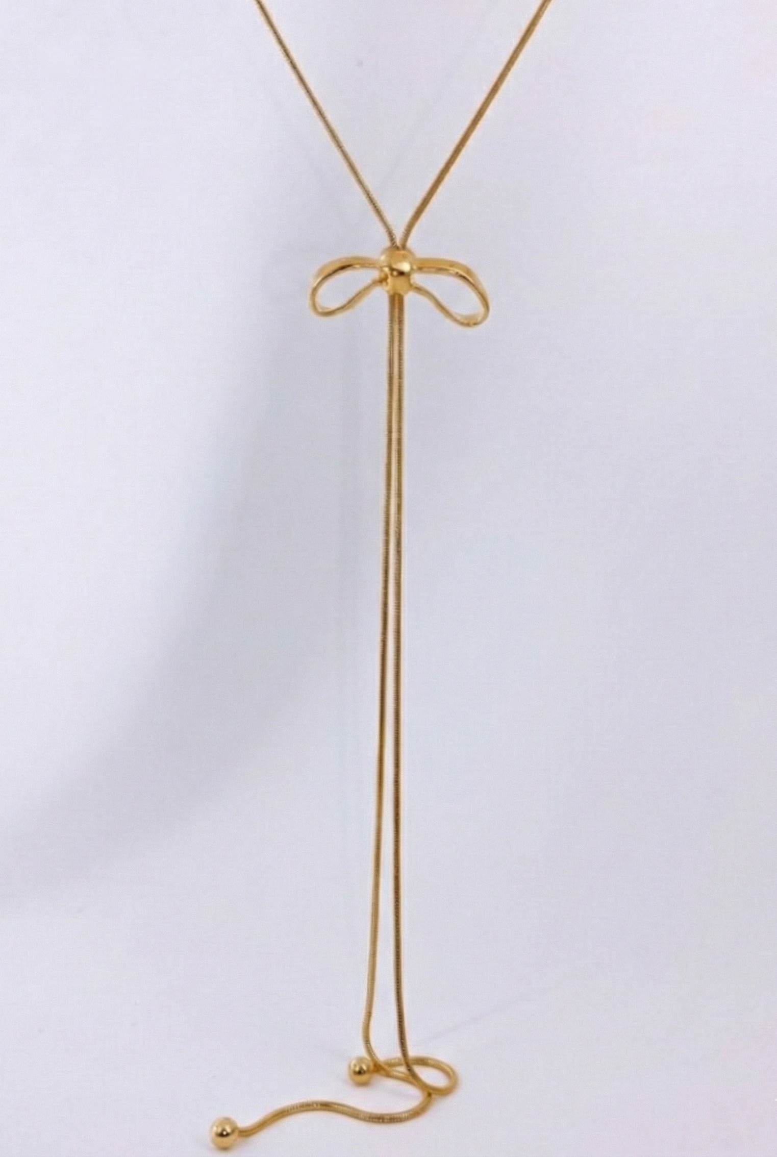 Close-up of gold ribbon bow pendant with sliding mechanism - 65cm adjustable lariat necklace