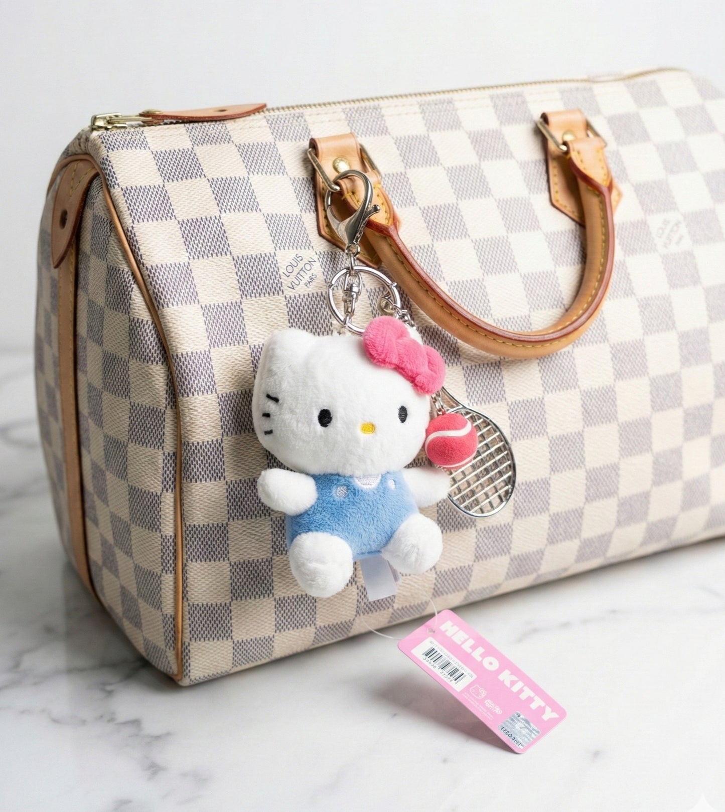 Hello Kitty tennis bag charm attached to Louis Vuitton Damier Azur handbag — kawaii Y2K luxury bag accessory