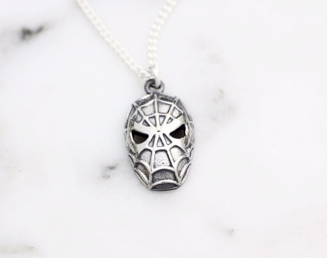 Flat lay of vintage style silver spider character necklace with intricate web details