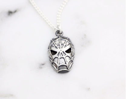 Flat lay of vintage style silver spider character necklace with intricate web details