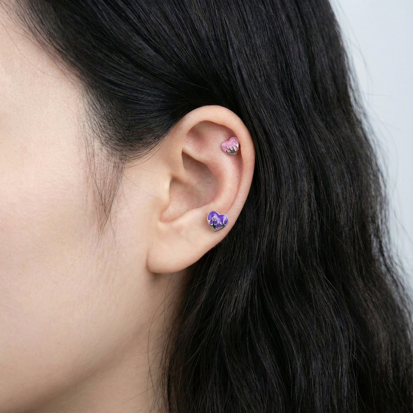 Purple melting heart piercing on inner conch and lobe demonstrating layered ear stack
