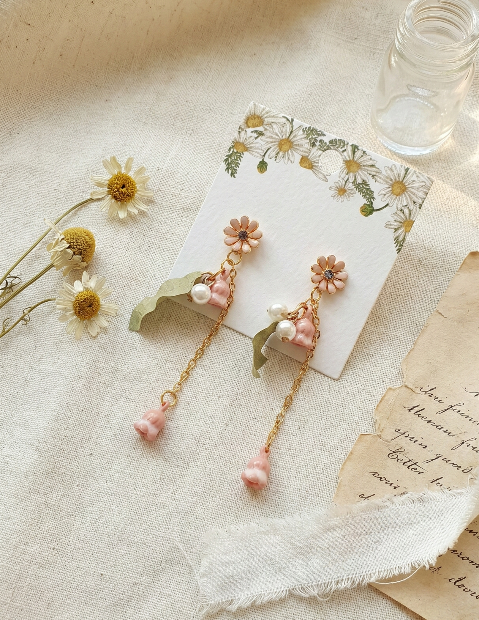 Close-up of pink flower drop earrings with pearls and green leaf charms.