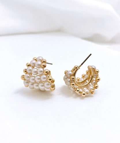Close-up side view of gold beaded heart hoop earrings with titanium post visible