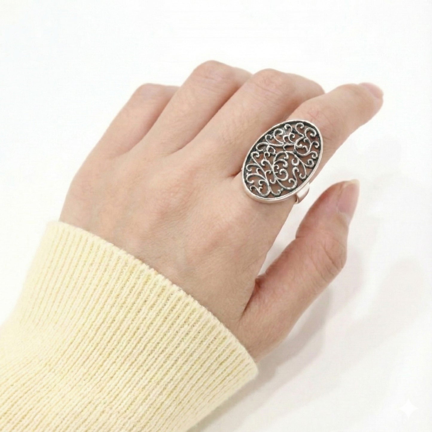 Side view of oxidized silver oval statement ring with cream knit sweater