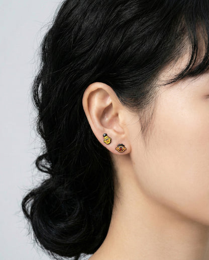 Model wearing Sesame Street Bert and Ernie character earrings in yellow and orange on earlobe