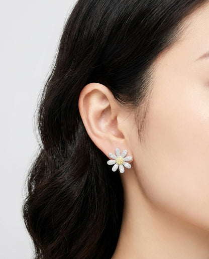Woman modeling large daisy flower earrings on ear - demonstrates size and sparkle on face