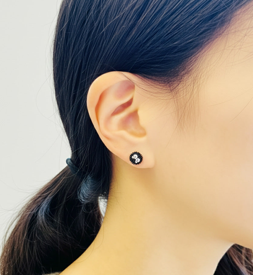Close-up of single classic Soot Sprite stud earring worn on earlobe showing detailed texture