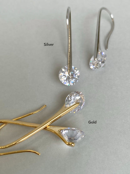 Close-up of silver and gold plated brass U-hook earrings with brilliant-cut cubic zirconia stones