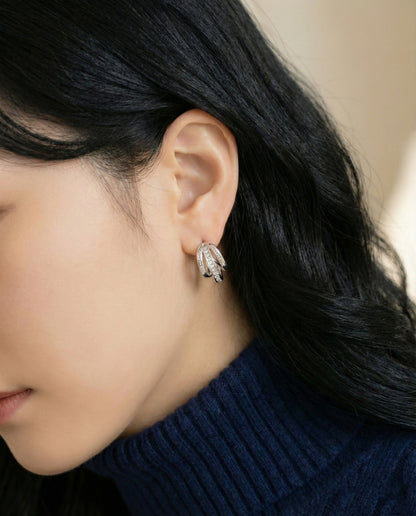 Close-up of silver triple layered baguette cubic zirconia huggie earrings on ear