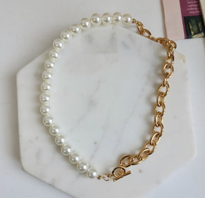 Overhead view of gold toggle choker with pearl and brass chain on white display