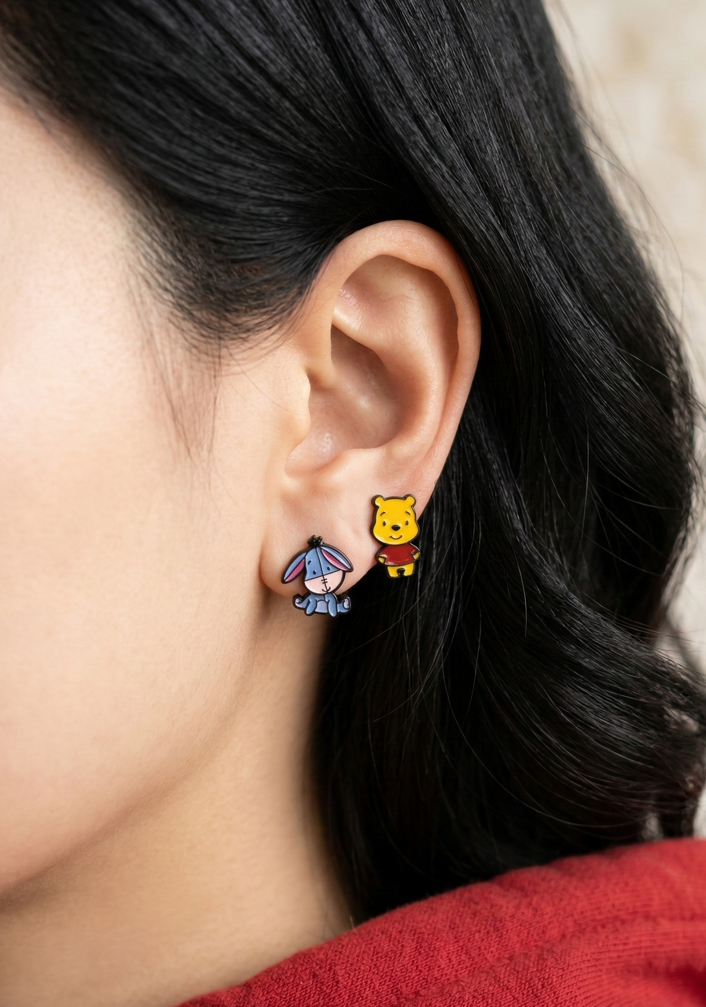 Side view of a woman wearing a mismatched cute Eeyore and Pooh two-way earring