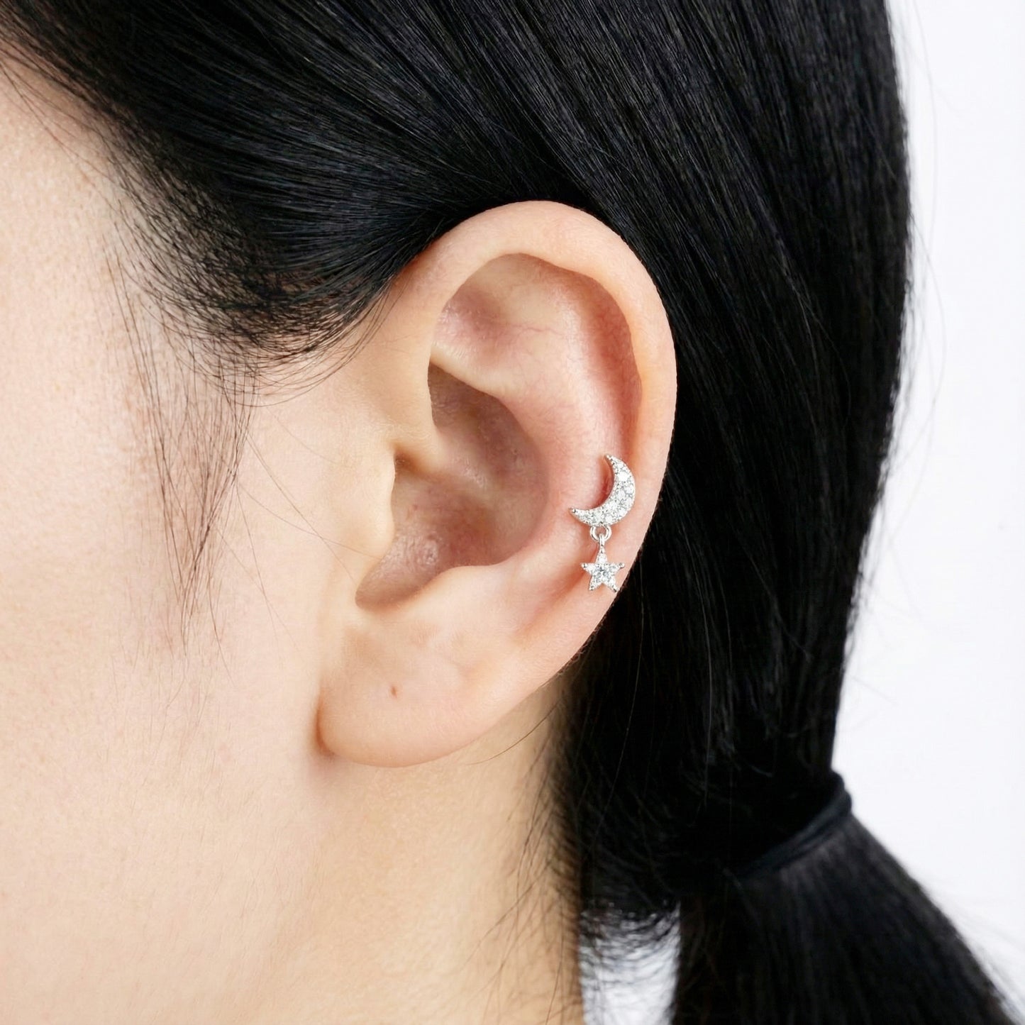 Silver moon-and-star barbell ball stud earring styled on the upper ear.