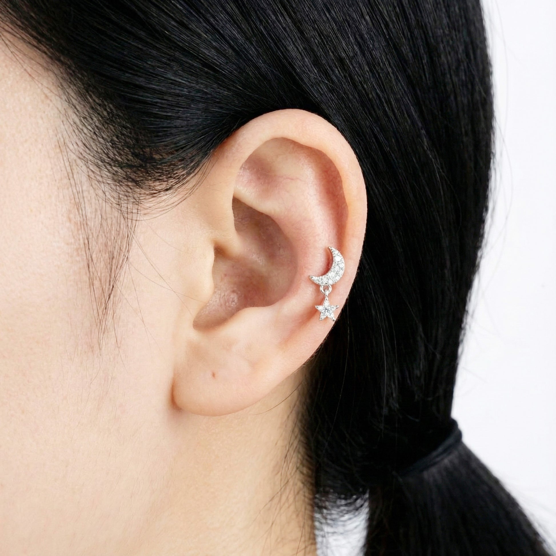 Silver moon-and-star barbell ball stud earring styled on the upper ear.