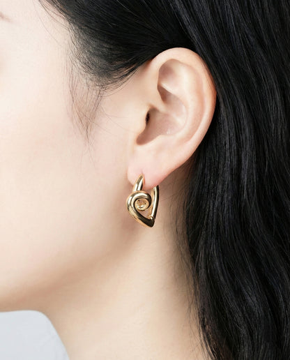 Close-up of gold twisted heart hoop earrings on ear, chunky dimensional knot design jewelry