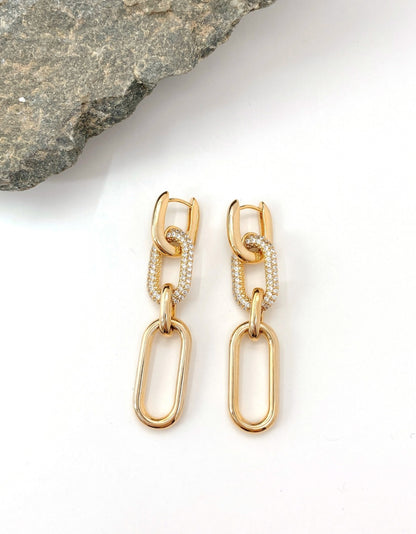 Close-up of gold pavé chain link drop earrings featuring sparkling CZ stones and polished brass finish