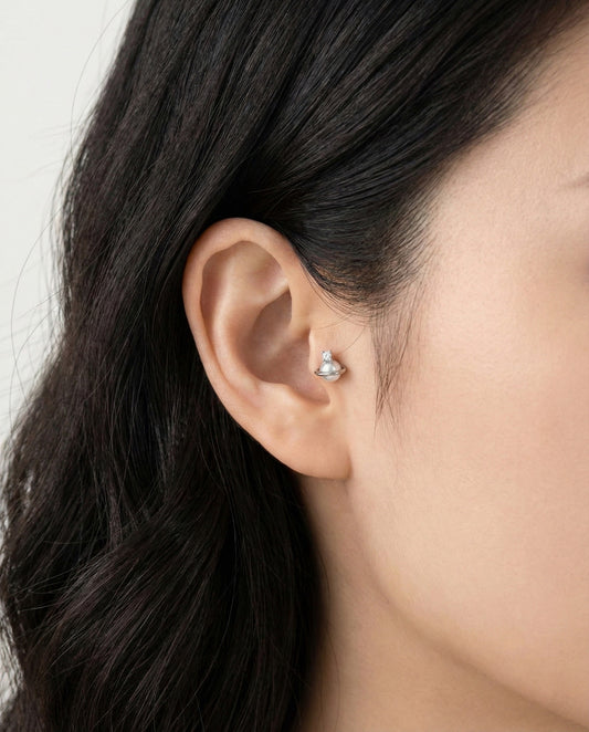 Silver Saturn planet pearl barbell piercing with cubic zirconia worn solo on earlobe