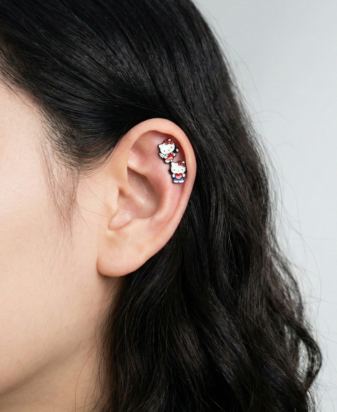 Hello Kitty cartilage earrings styled on helix and tragus, perfect for creating a kawaii ear curation