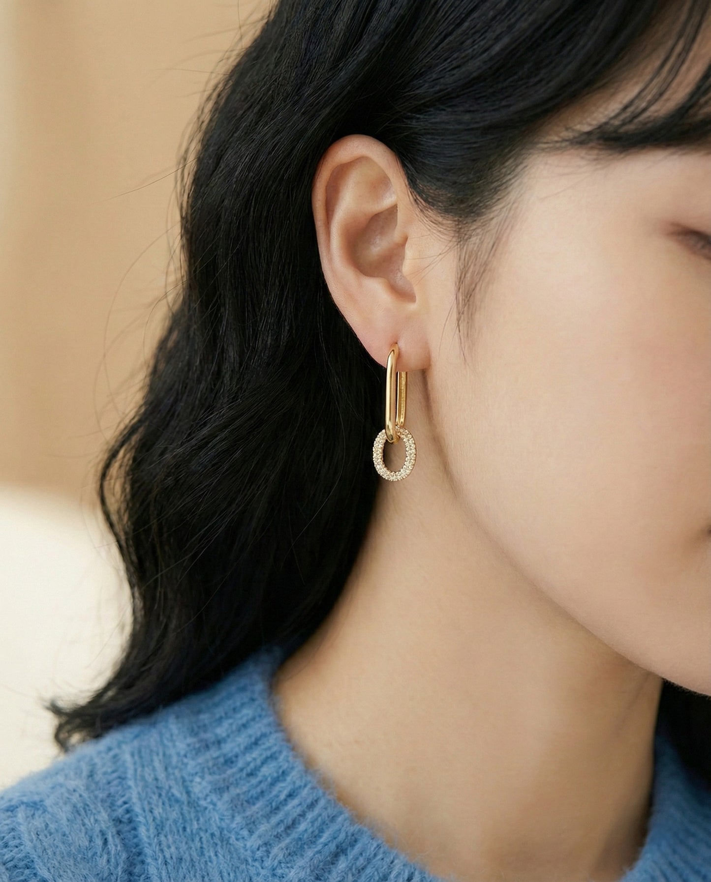 Woman wearing gold oval link drop earrings with blue knit sweater, bottom pave style