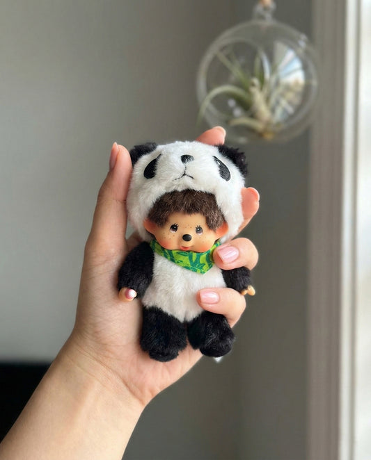 Hand holding cute panda Monchhichi plush keychain with bamboo scarf