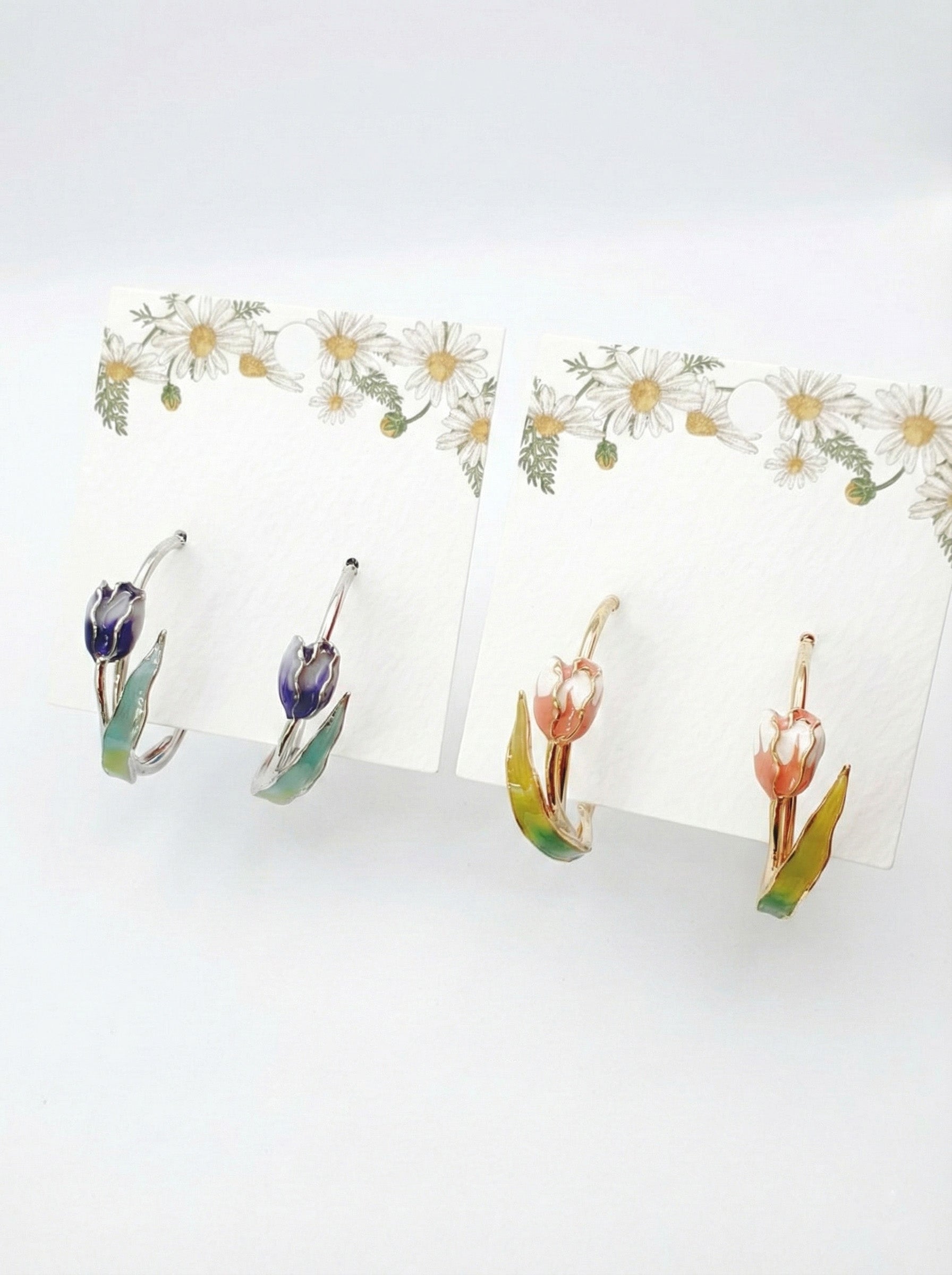 Two pairs of handmade tulip hoop earrings in blue and pink watercolor gradients