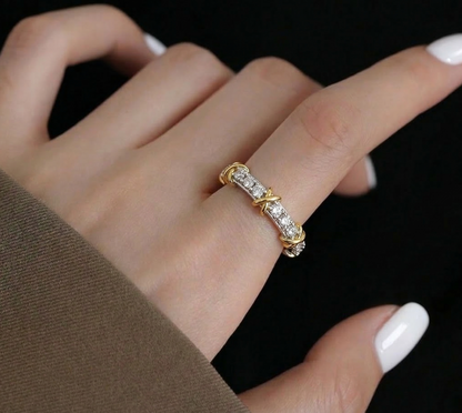 Close-up of the 925 sterling silver two-tone X-cross ring worn on the index finger against a black background, highlighting the gold cross details and cubic zirconia sparkle