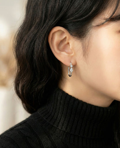 Woman in black turtleneck sweater wearing silver bezel-set double CZ square hoop earrings