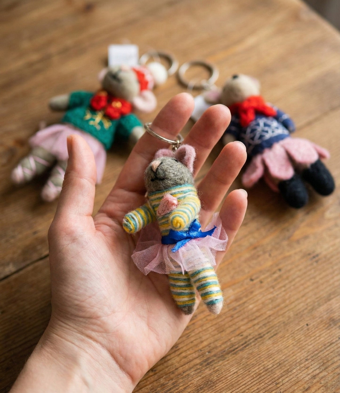 Hand holding striped ballerina mouse keychain showing soft wool texture and detailed tulle tutu skirt