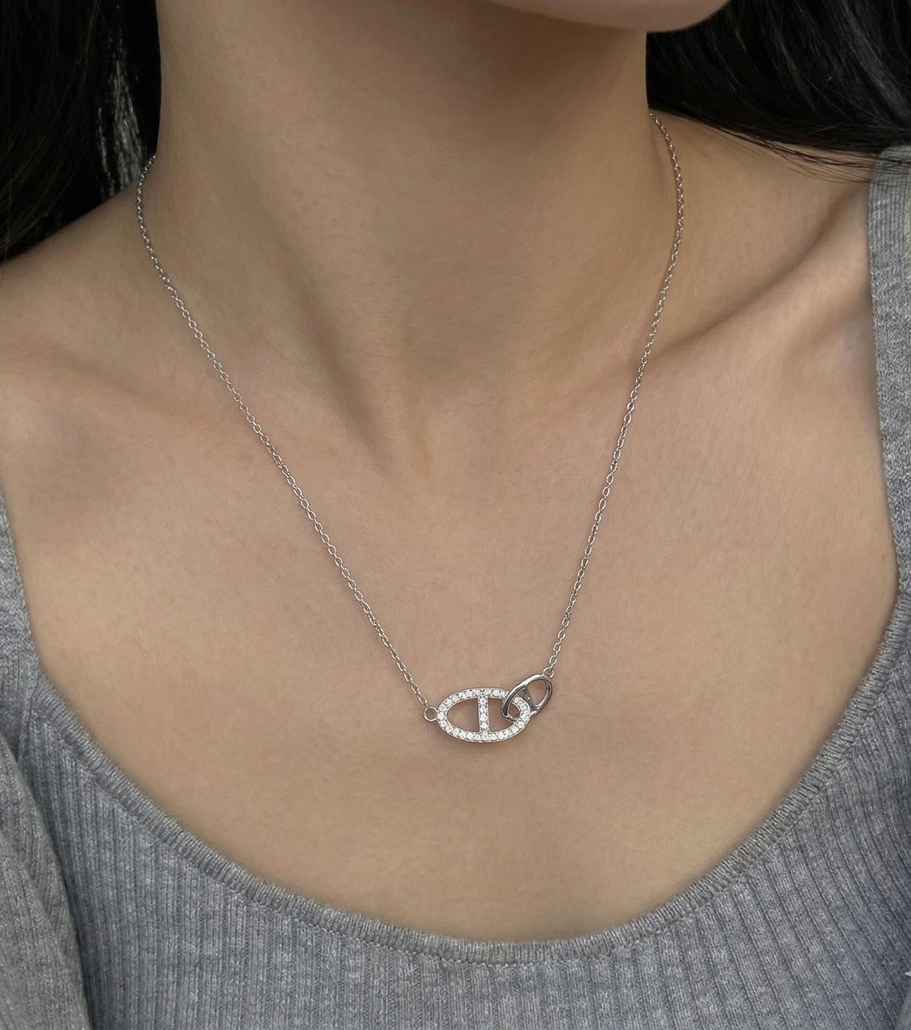 Model wearing 925 sterling silver interlocking double ring necklace with a gray ribbed round-neck top, collarbone-length styling