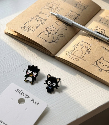Flat lay of cute character earrings with cat sketch notebook and pen, artsy aesthetic kawaii jewelry photography