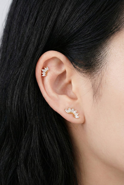 Model wearing curved wing marquise cubic cartilage piercing on helix with layered earrings