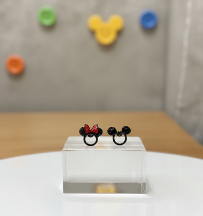 Close-up of asymmetric Mickey and Minnie black cubic zirconia stud earrings on transparent acrylic stand