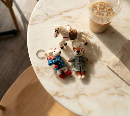 Woman holding camel leather hobo bag decorated with wool felt animal bag charms