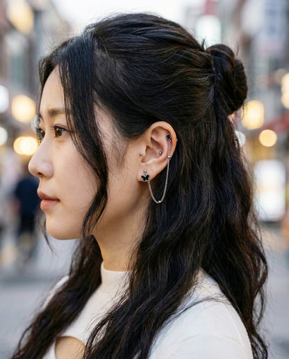
Side view of surgical steel chain piercing connecting helix to lobe with black butterfly charm
