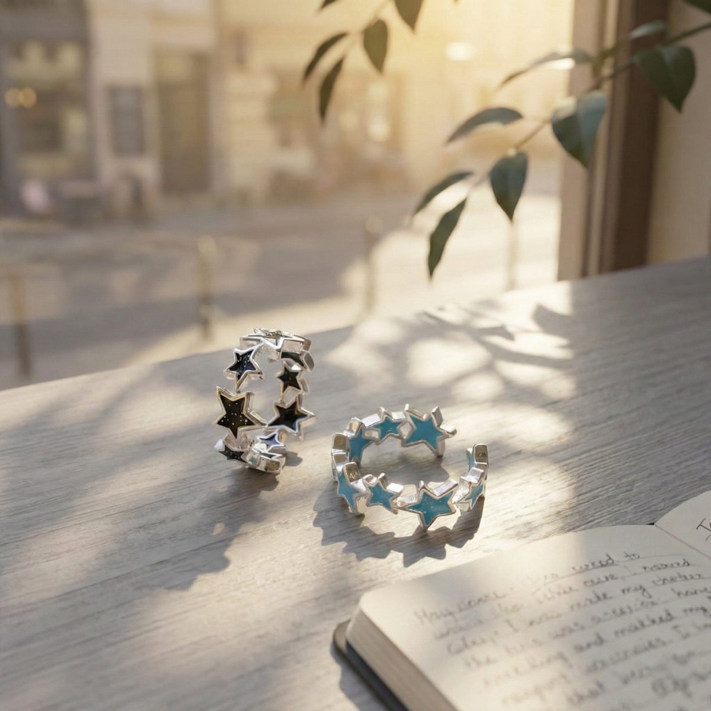 Close-up of black and sky blue glitter enamel star rings on white wooden table