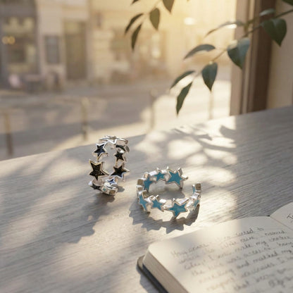 Close-up of black and sky blue glitter enamel star rings on white wooden table