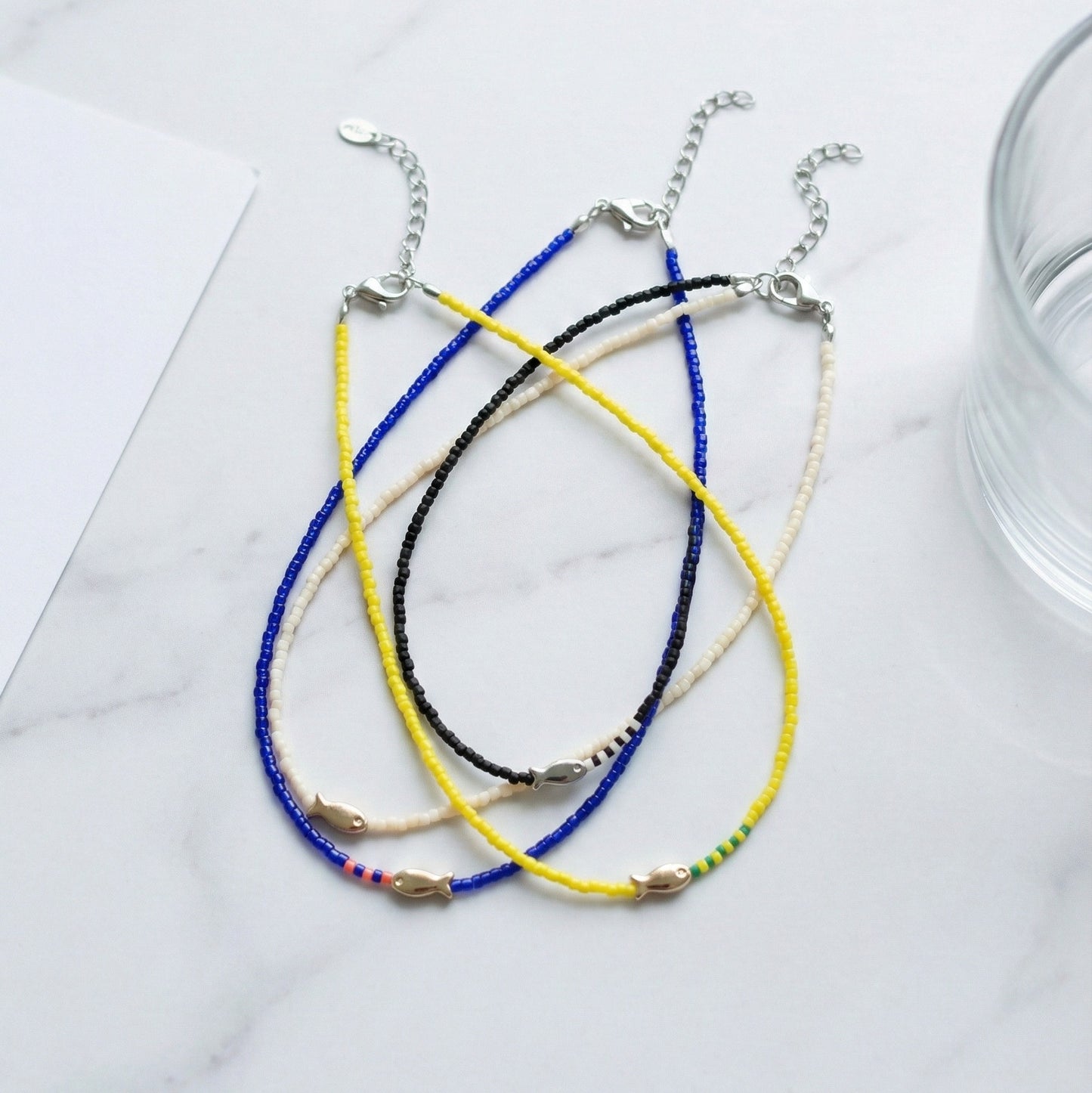 Colorful seed bead fish choker necklaces with adjustable chain featuring blue yellow black and ivory beads