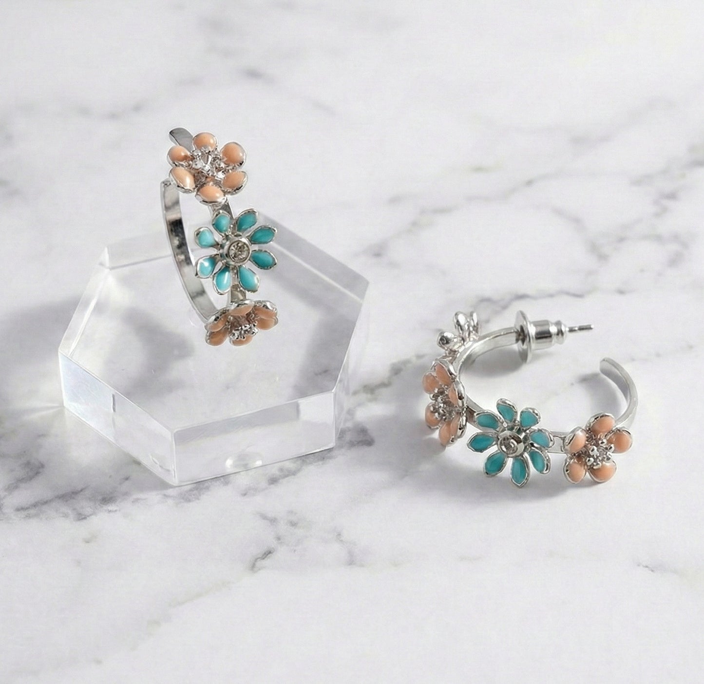 Close-up of mint garden enamel flower hoop earrings with titanium post on marble surface