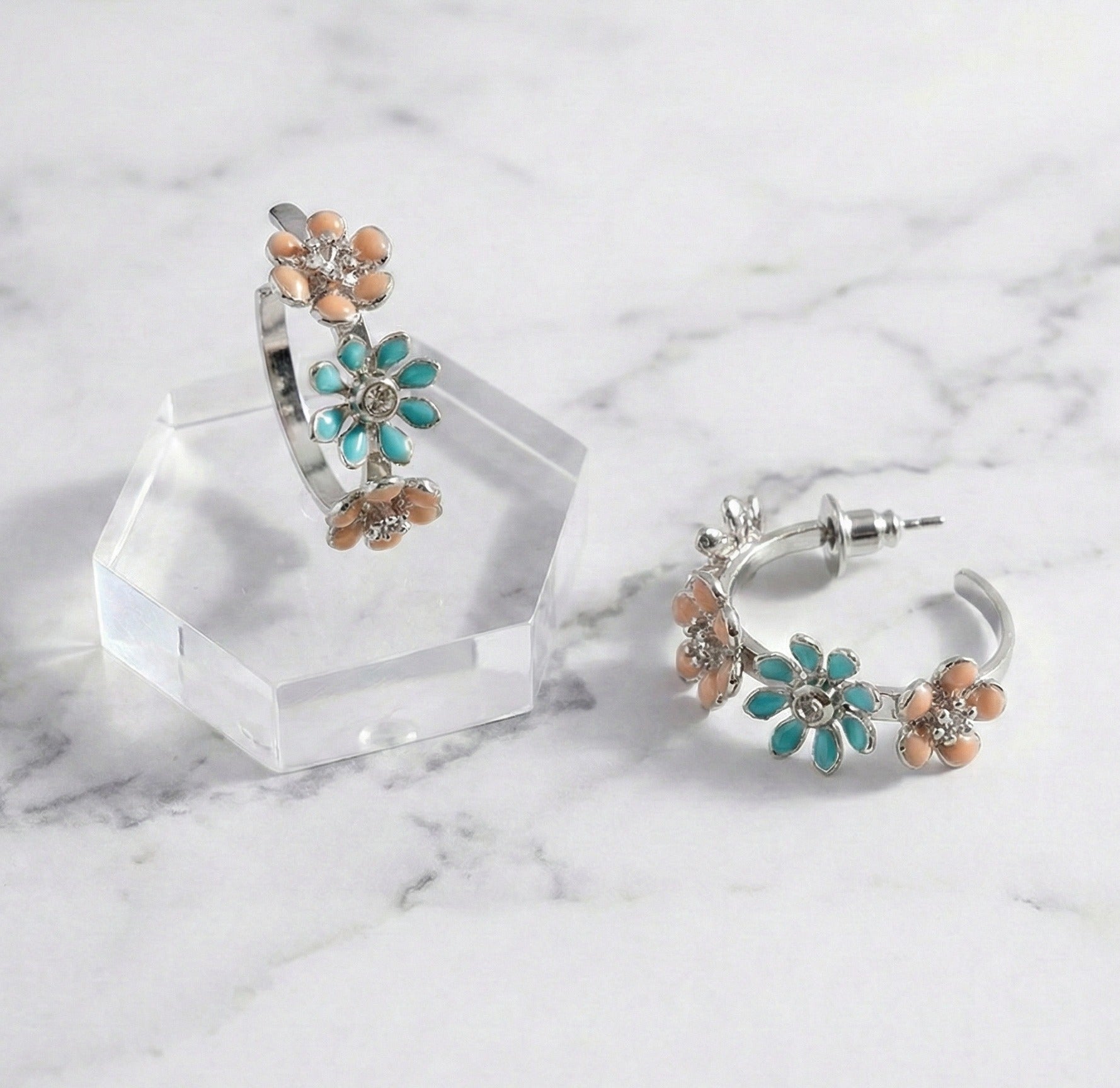 Close-up of mint garden enamel flower hoop earrings with titanium post on marble surface
