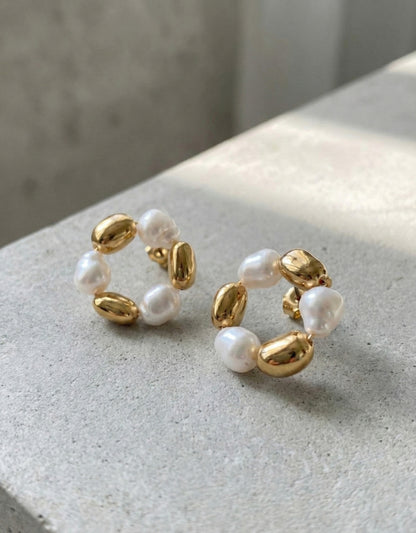 Close-up of gold baroque freshwater pearl and metallic bean wreath hoop earrings showing detailed craftsmanship