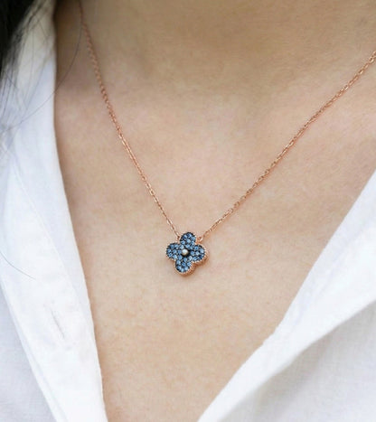 Woman wearing deep blue cubic zirconia clover necklace, rose gold pendant closeup on collarbone