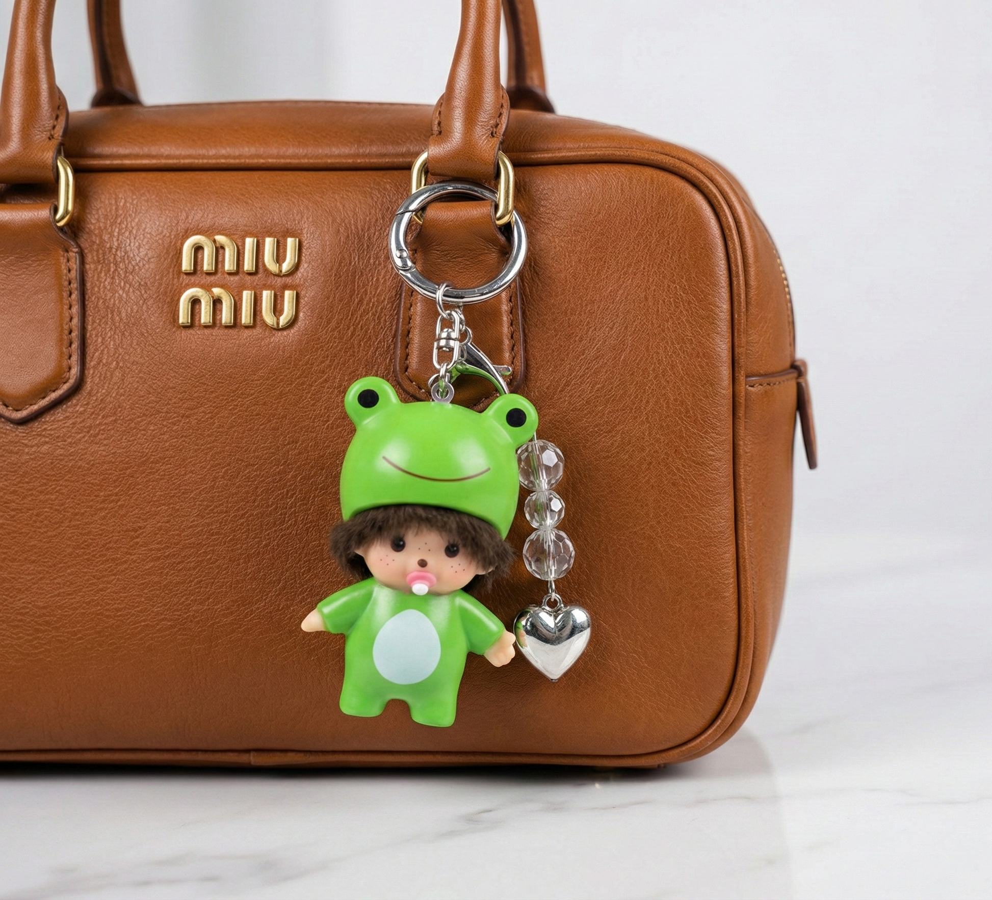 Kawaii frog doll bag charm with crystal beads and silver heart attached to tan Miu Miu leather handbag