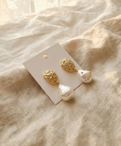  Gold baroque pearl drop earrings with hammered texture on beige linen fabric
