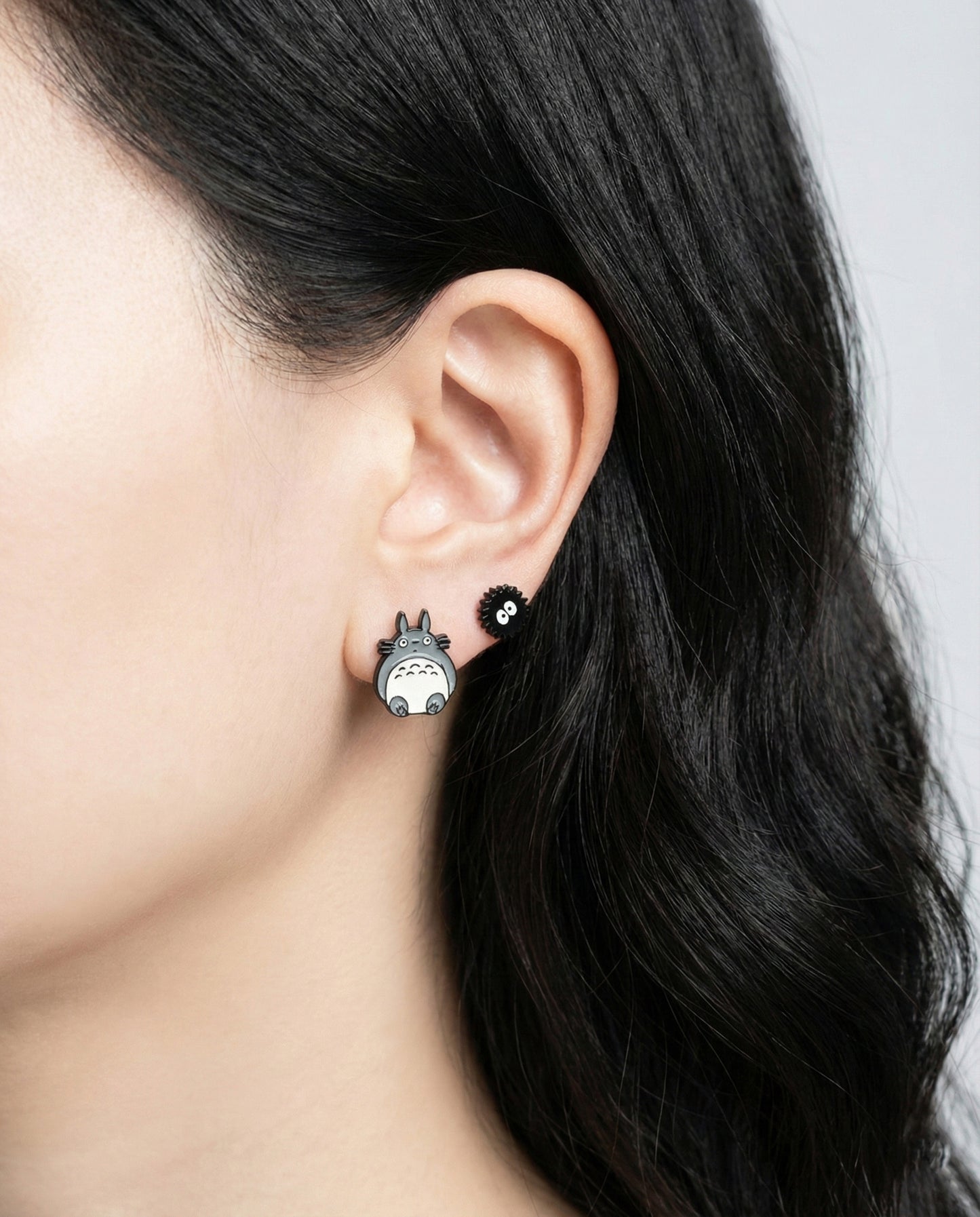 Totoro and Soot Sprite stud earrings worn on ear showing layered piercing style
