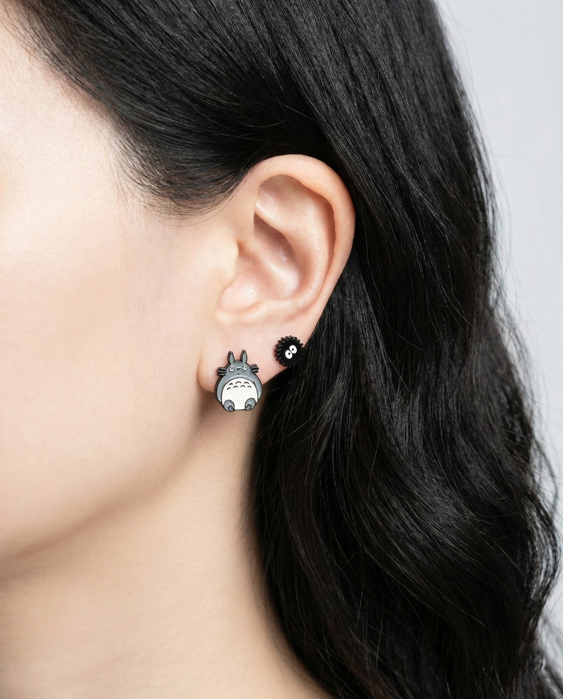 Totoro and Soot Sprite stud earrings worn on ear showing layered piercing style