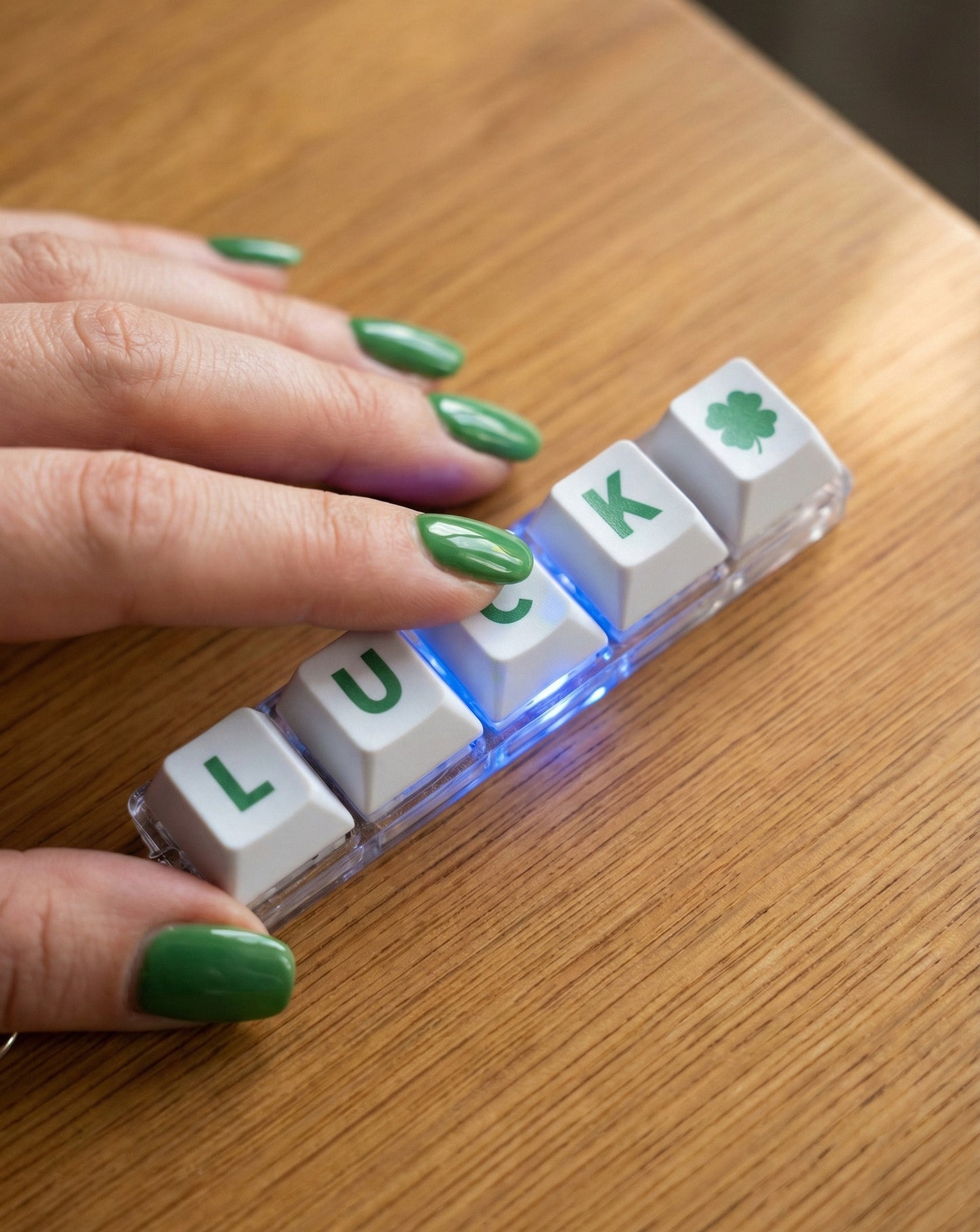 Hand pressing mechanical switch keychain with blue LED light glowing through transparent case