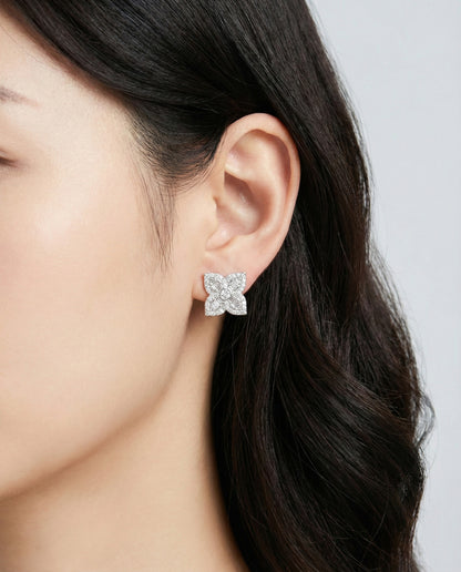 Silver floral CZ stud earrings with baguette and round cut stones worn on ear