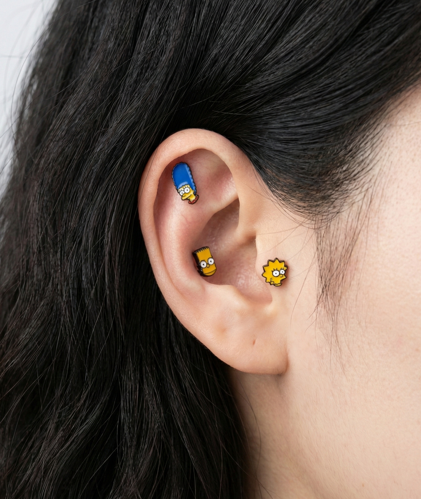 Bart Simpson and Lisa Simpson enamel stud earrings on ear, showing cartilage and lobe placement, Korean handmade jewelry